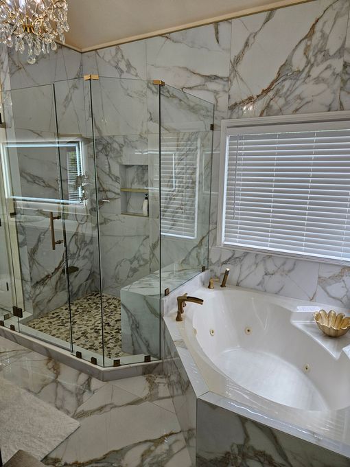 A bathroom with marble walls and a tub and shower