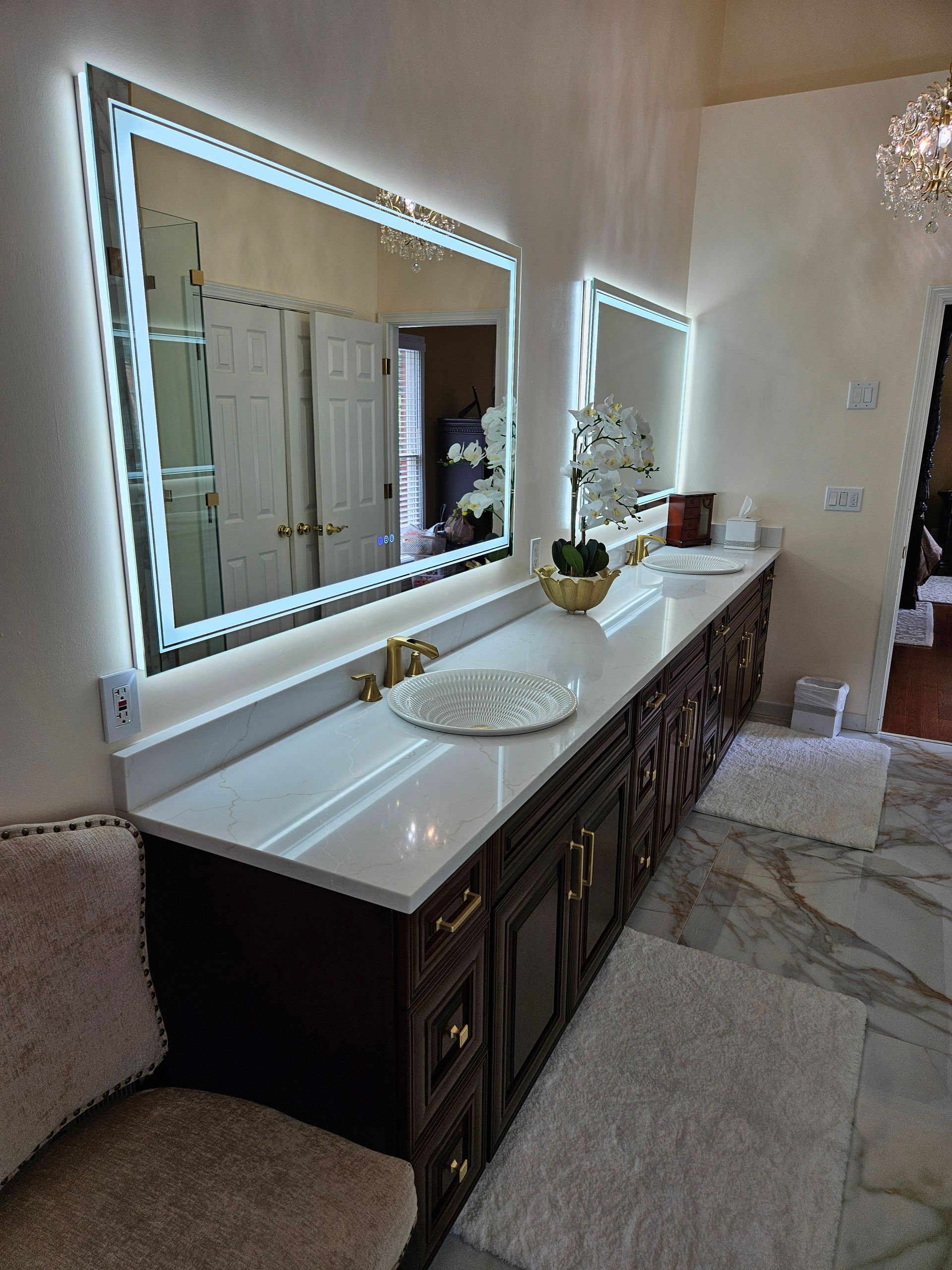 A bathroom with two sinks , two mirrors , and a chair.