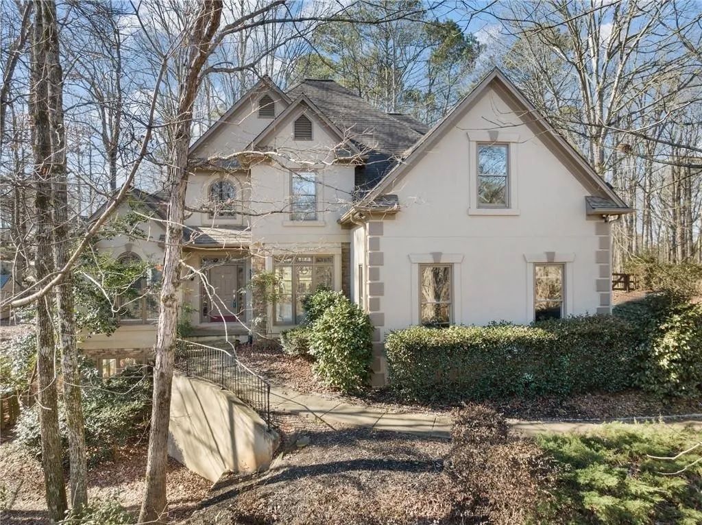 A large white house is surrounded by trees and bushes